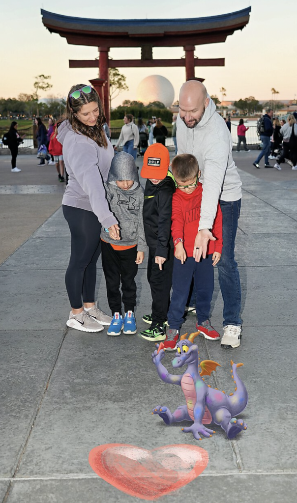 Mom and dad with their two young sons pointing and laughing near a colorful dragon statue during a family vacation.