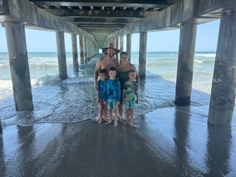 Family of five standing under a pier on the beach in Myrtle Beach, South Carolina