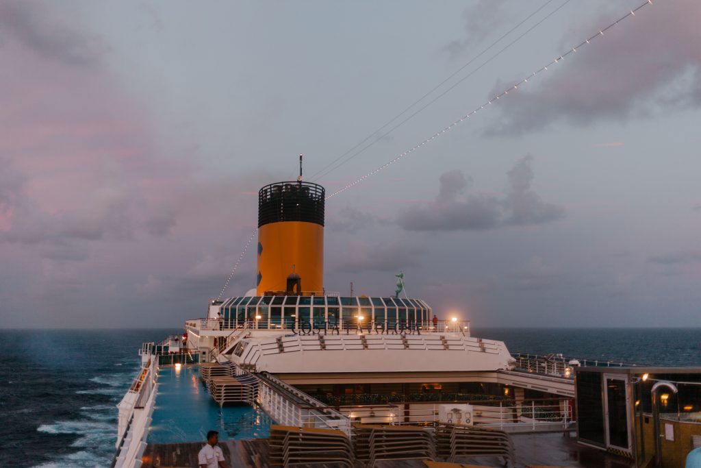 Cruise ship deck and pool area at dusk, showing the relaxed onboard experience of a cruise vacation.